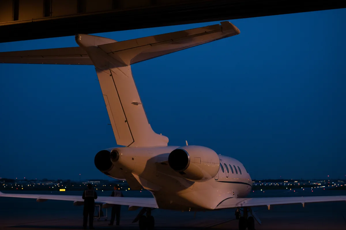 Detail view of the T-tail and rear engine of a small jet at dusk.