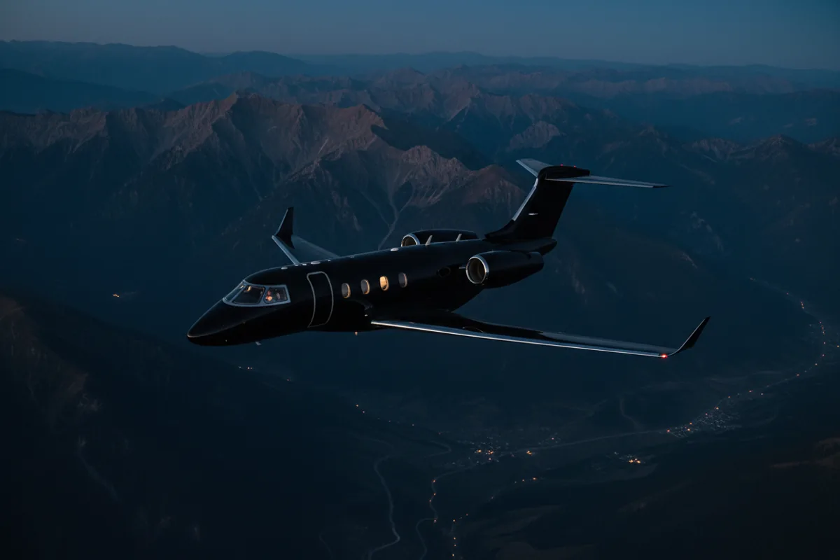 A private jet flies over a mountain range at sunset.