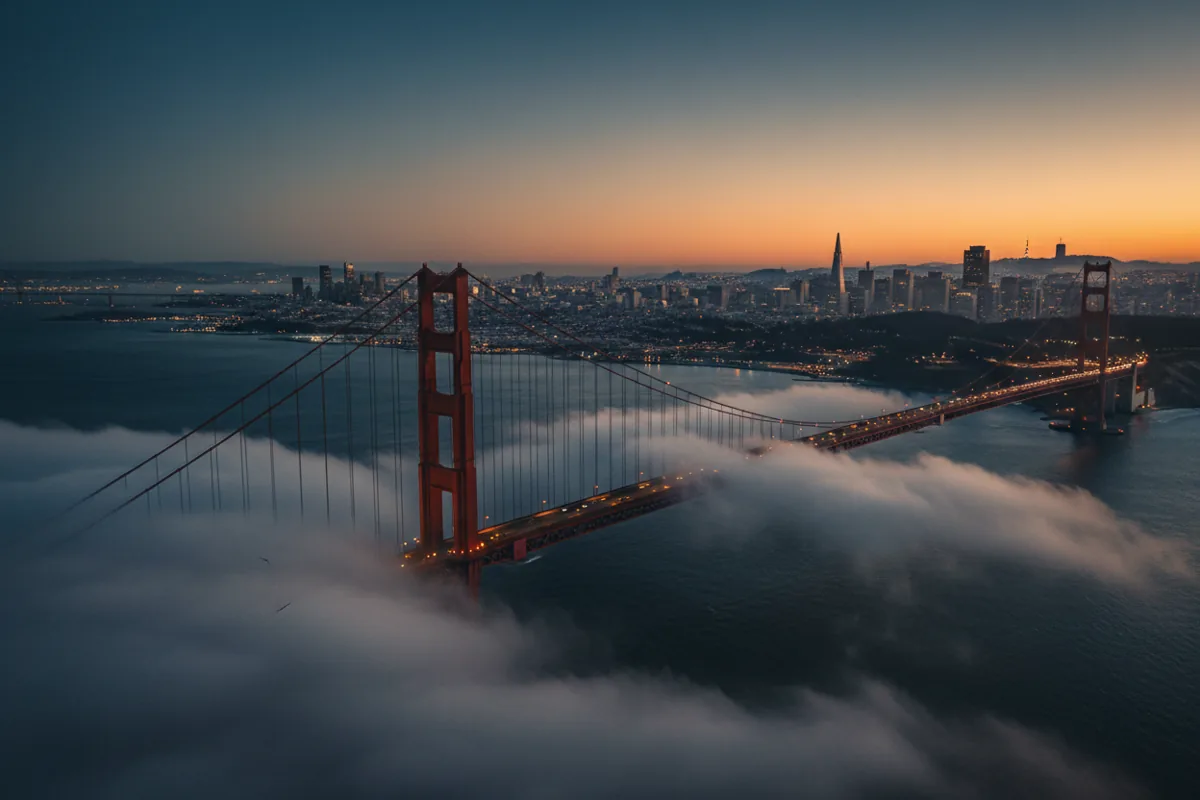 Aerial view of the Golden Gate Bridge and the San Francisco skyline at golden hour.