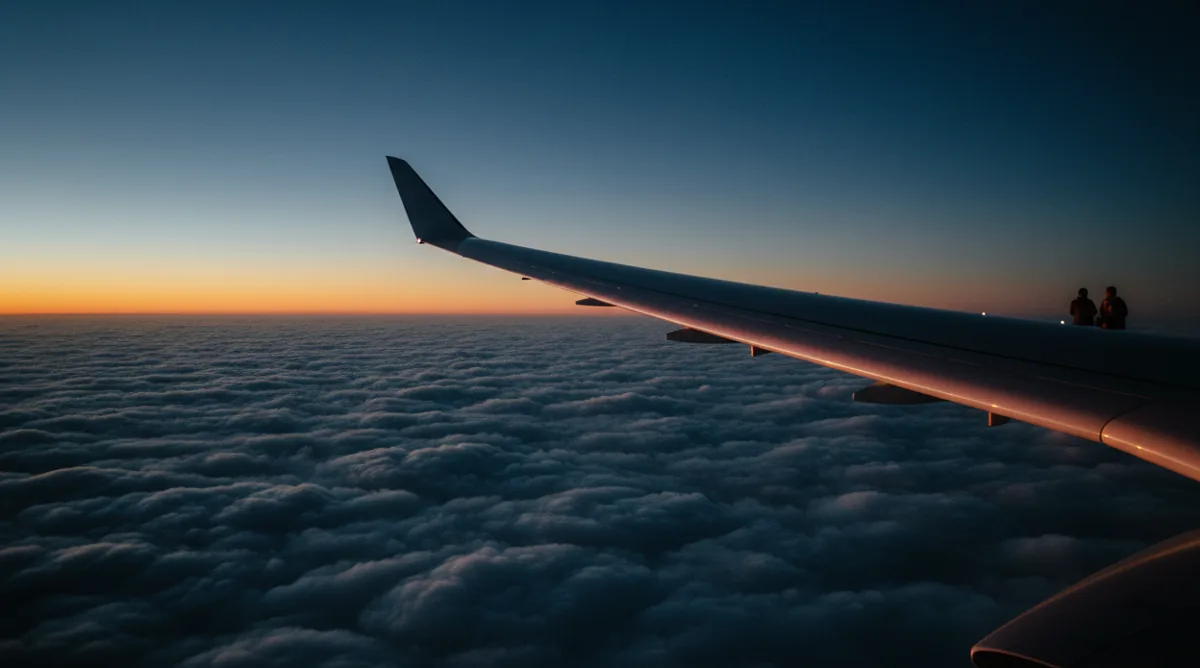 The wing of a jet in flight above a sea of clouds at sunrise, illustrating long-distance travel.