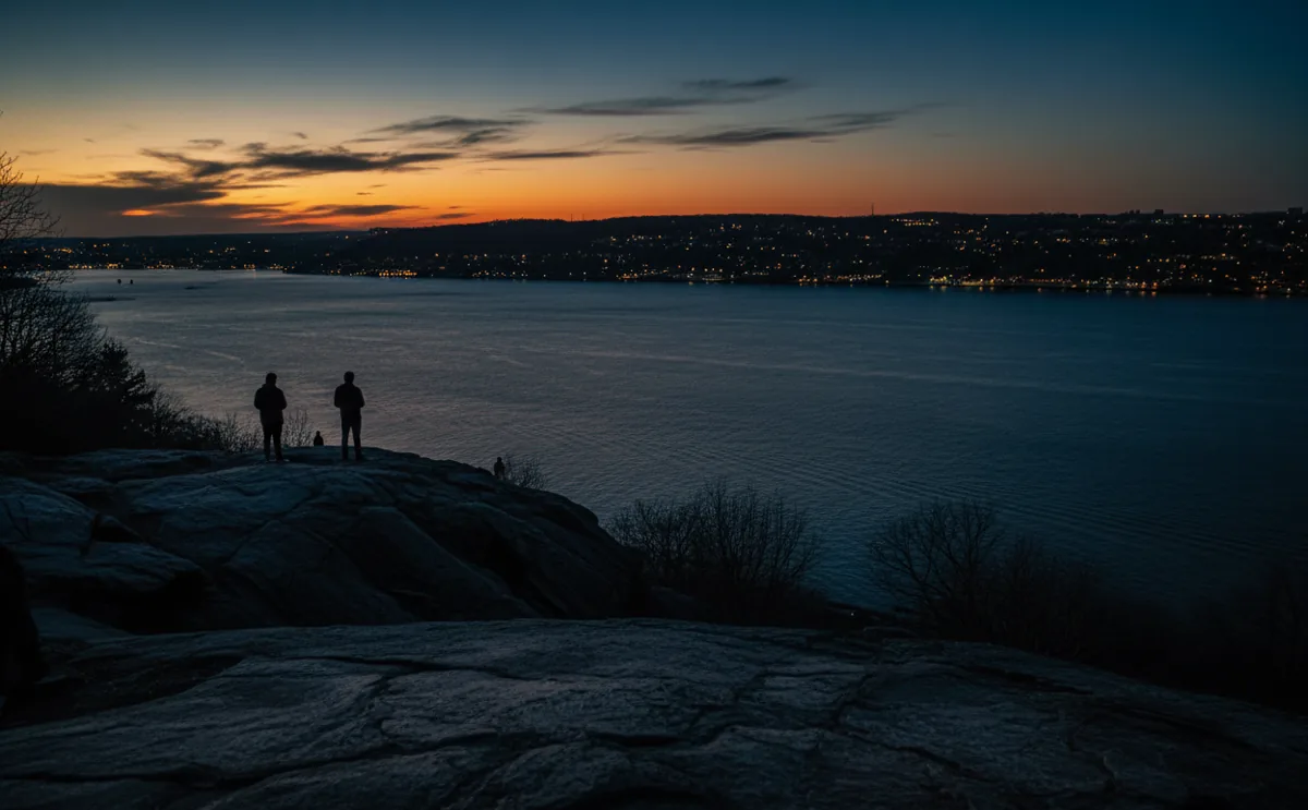 A view over the Hudson River from a park in Washington Heights at dusk, with the sky turning a deep blue.