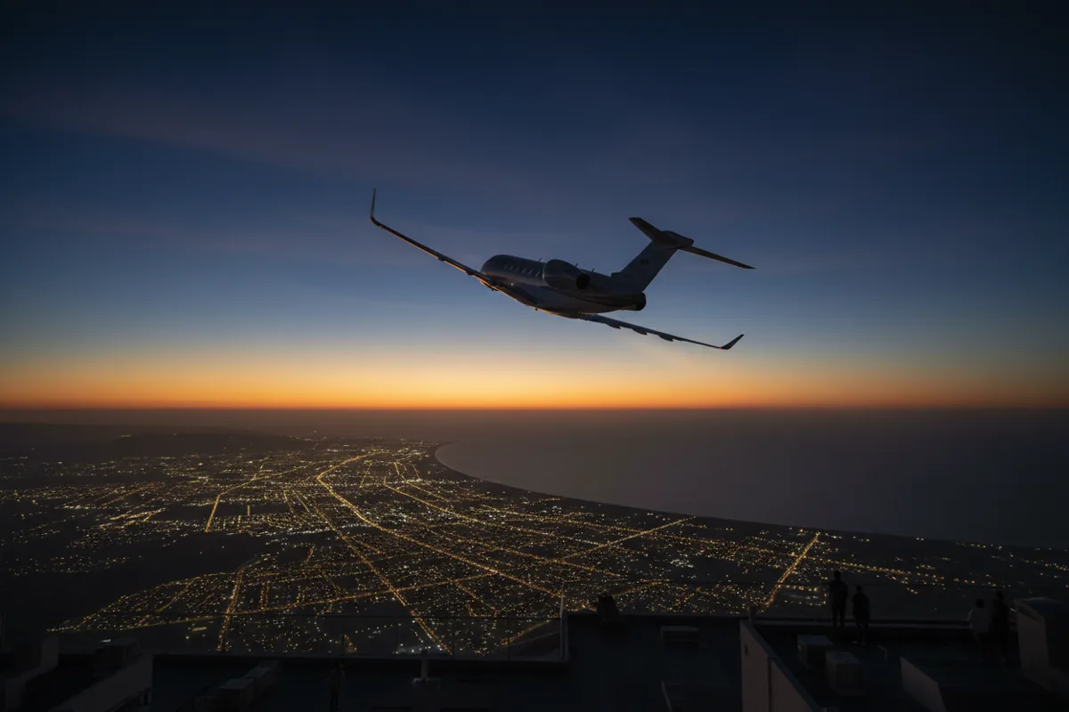 A private jet in a steep climb after takeoff, flying over a city at dusk.