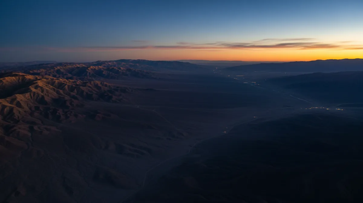 Aerial view of a vast desert landscape with mountains at dusk.