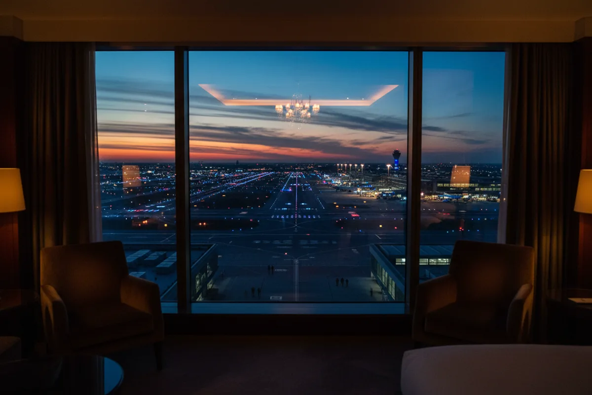 Airport runways lit up at night, as seen from a high-floor hotel room window.