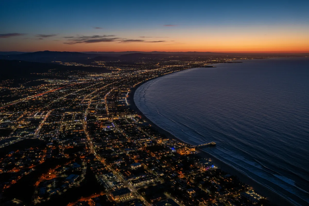 An aerial view of the Southern California coastline at twilight, with city lights glowing along the ocean.