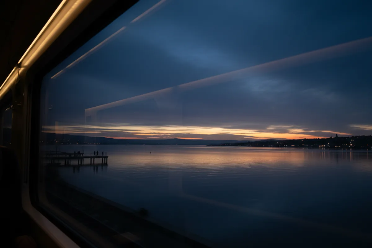 View of the calm ocean and overcast sky from a clean train window.