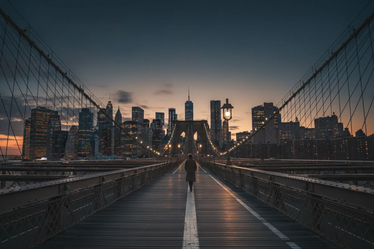 The pedestrian walkway of the Brooklyn Bridge at dusk, looking towards the Manhattan skyline.